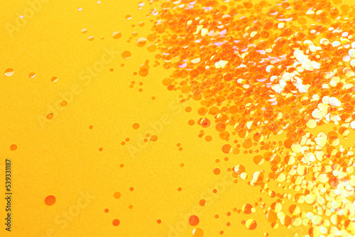 Shiny bright glitter on orange background. Space for text