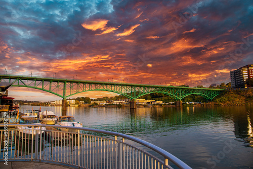 a gorgeous autumn landscape along the Tennessee River with boats docked and the Gay Street Bridge over the water with powerful red clouds at sunset in Knoxville Tennessee USA photo