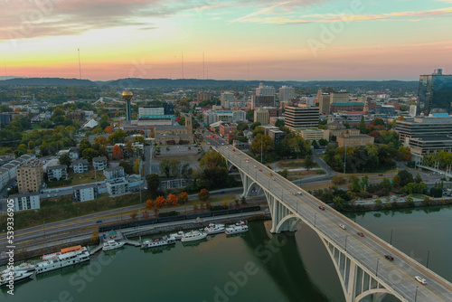 aerial shot of the Henley Street Bridge over the Tennessee River surrounded by autumn colored trees, lush green trees and office buildings with powerful clouds at sunset photo