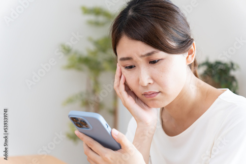 スマホを見て落ち込む女性
