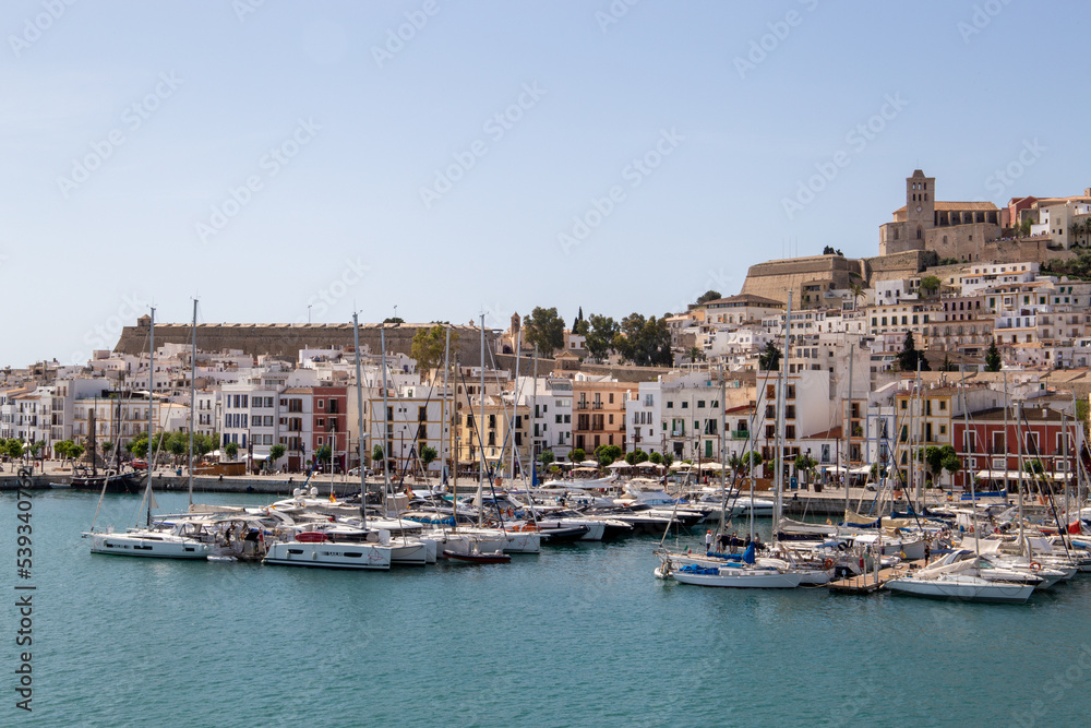 ibiza city seen from the sea, port with boats on the pier of ibiza with a church in the background