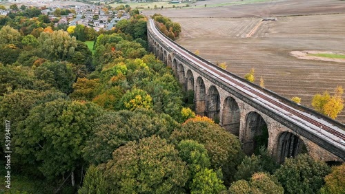 Drone footage of the Penistone Railway Station and stone built viaduct near Barnsley, South Yorkshire. Showing a ploughed field, bridge, woodland and railway tracks. photo