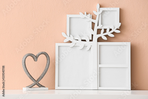 Family tree with photo frames and decor on table near beige wall © Pixel-Shot
