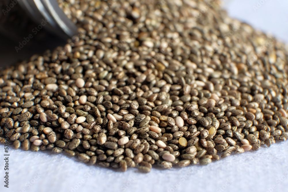 Detail of chia seeds scattered in pile on white background. Detail of chia seeds scattered in pile on white background.