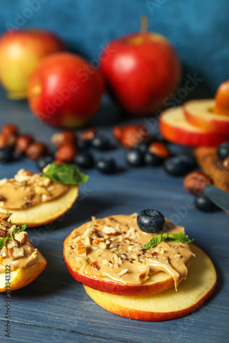 Fresh apple rounds with nut butter on color wooden table, closeup