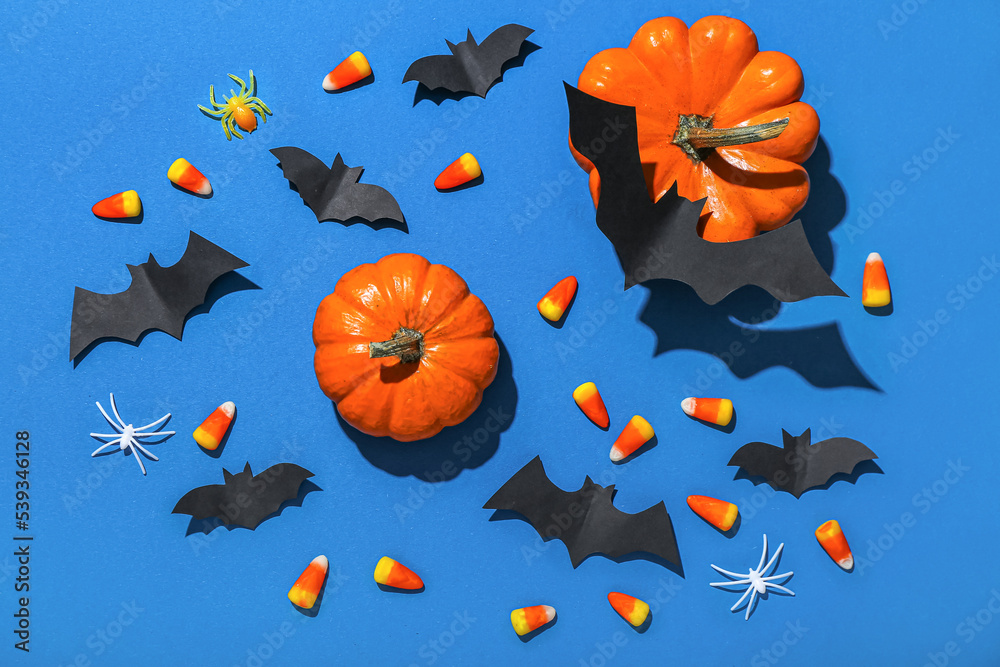 Paper bats with Halloween pumpkins and candy corns on blue background Paper bats with Halloween pumpkins and candy corns on blue background