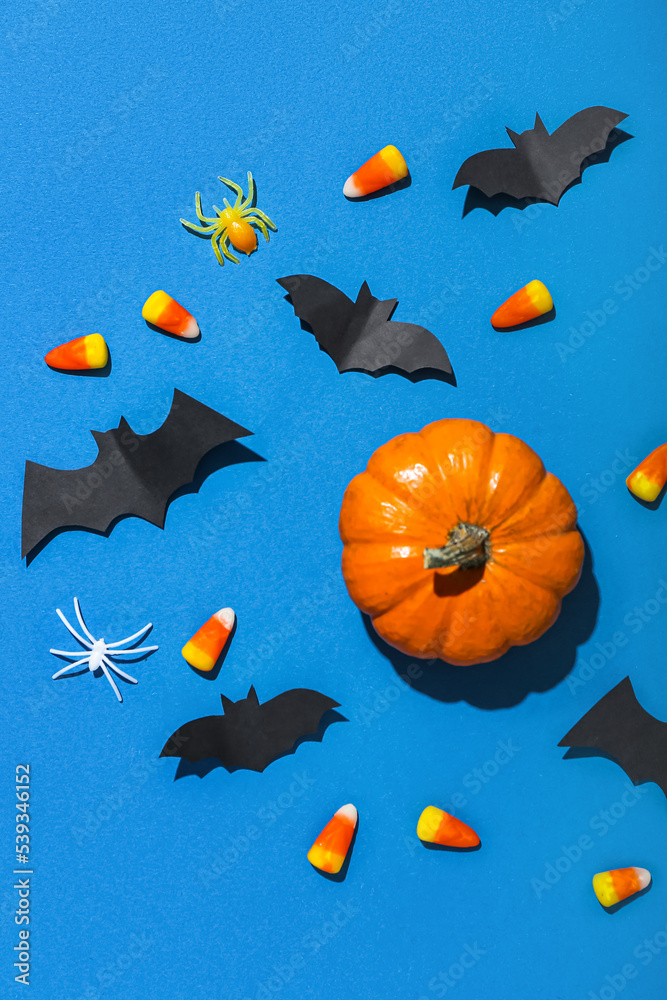 Paper bats with Halloween pumpkin and candy corns on blue background Paper bats with Halloween pumpkin and candy corns on blue background