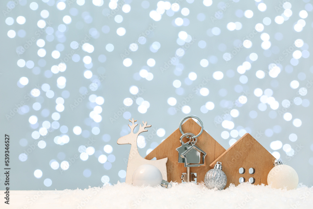 House figures with key and Christmas decor on table against blurred lights