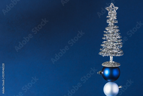 Christmas toys and a Christmas tree made of silver tinsel on a dark blue background. Unusual Christmas tree