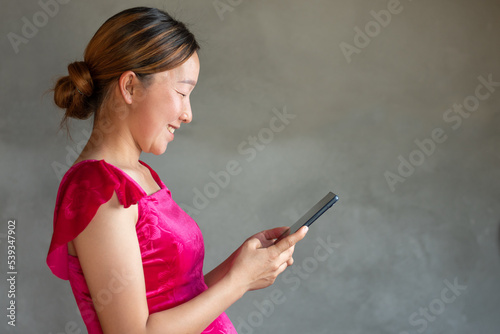 A medium shot of pregnancy women is video call with doctor on her mobile with smiling, cement wall background, mother and newborn childbirth concept copy space for individual text and design