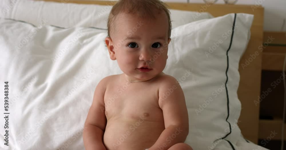 Baby girl 1 year old sitting up in bed looking towards camera Stock ビデオ
