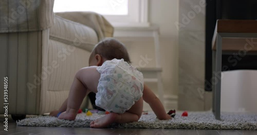 Baby girl playing with toys in living room sits down on diaper - wide shot