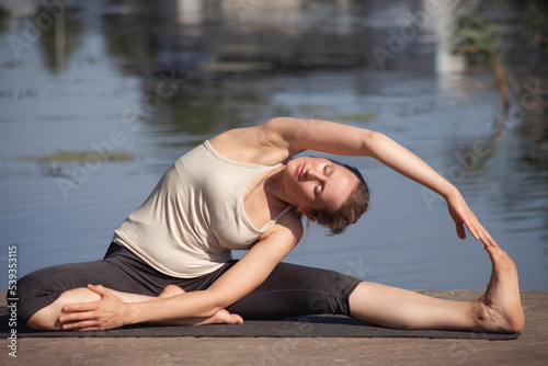 young naked woman practices yoga on the beach