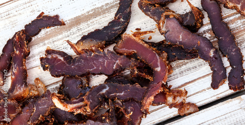 
Sliced traditional South African biltong or cured meat on rustic white wooden surface
 photo