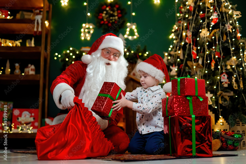 Little child in Santa's hat takes out giftboxes from Santa claus sack. Christmas time. New Year concept