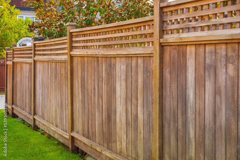 Nice wooden fence around house. Wooden fence with green lawn. Street photo