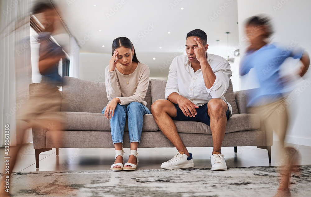 Fototapeta premium Headache, kids running and parents on a sofa in a living room, suffering stress, anxiety and adhd children. Family, autism and burnout crisis with woman and man in mental health and energy problem