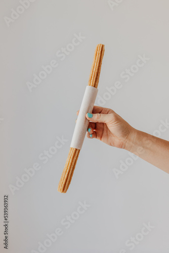 Hand holding churro on white background photo