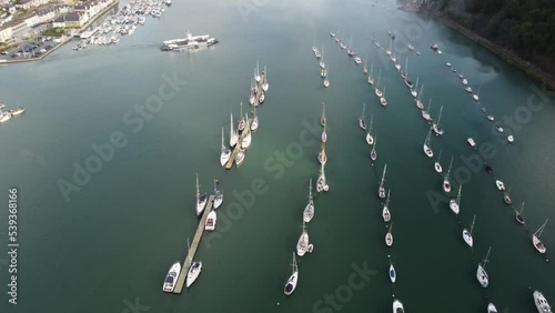A tilt reveal drone shot of the River Dart looking misty up river, as the Dartmouth to Kingswear Higher Ferry crosses from left to right. photo