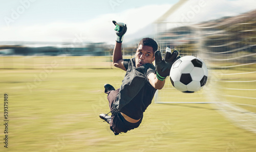 Soccer, sports and goalkeeper with a man saving a shot, goal or score during a game on a grass pitch field. Fitness, football and training with a male athlete making a save during a practice session
