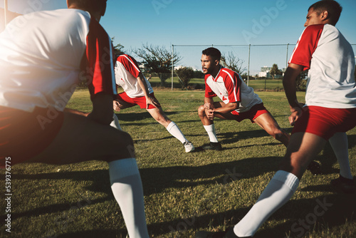 Soccer field, men and team stretching legs for match warm up, practice or game. Sports, football and group stretch outdoors on pitch in preparation for exercise, training or fitness workout on grass. photo