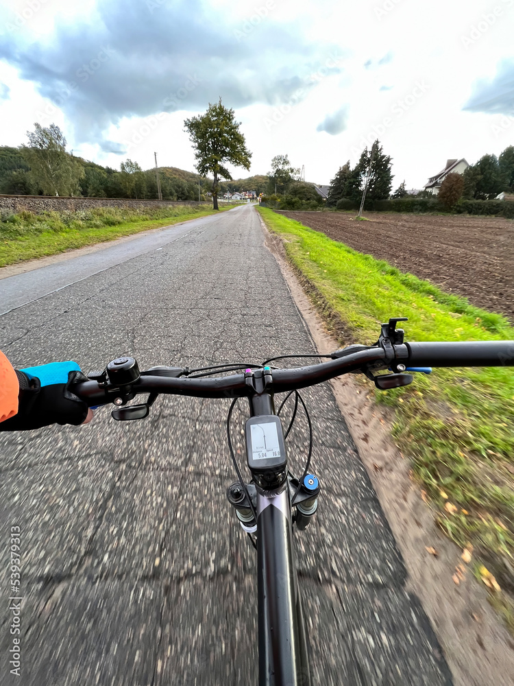 Holding the bike handlebar with one hand. Close-up of bicycle handlebar. First-person view of bicycle riding. A man is riding a bike. Concept of commuting by bicycle
