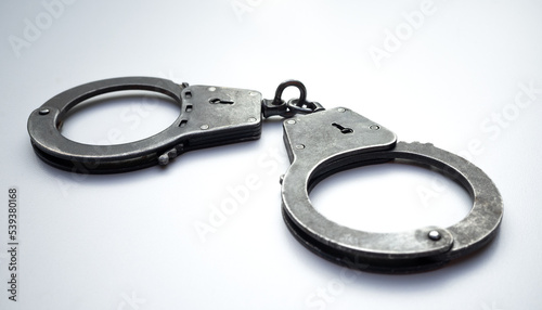 Large metal handcuffs on white isolate. White background with police handcuffs.A means to detain a criminal. Arrest of the suspect.Criminal actions. Detention.