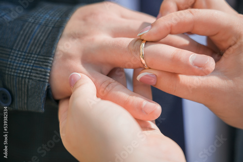 A woman puts a wedding ring on a man's finger. Close-up.