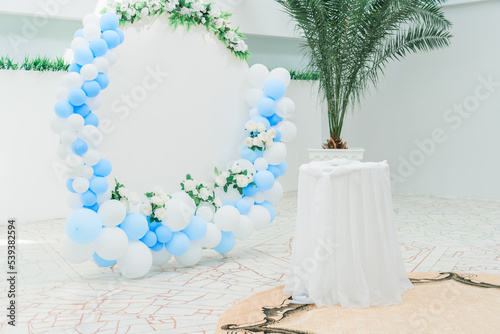 Decoration of the photo zone with balloons and a press- ox in the form of a circle. Balloons of blue and white color in the design of the photo zone.