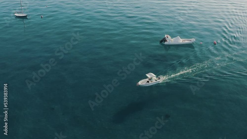 Aerial view of a speedboat moving forward close to other moored boats in the Ionian Sea, Calabria, Italy.