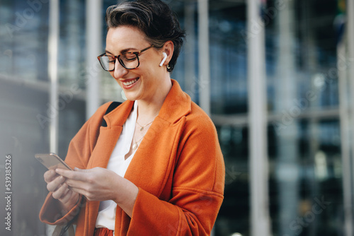Smiling businesswoman reading a text message on her phone while commuting to her office in the city