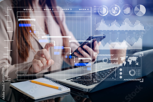 Businessman hand Project manager working and update tasks and Gantt chart scheduling virtual diagram.with smart phone, tablet and laptop in office.