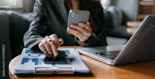 Businesswoman hands working with finances about cost and calculator and laptop with tablet, smartphone at office © Nuttapong punna