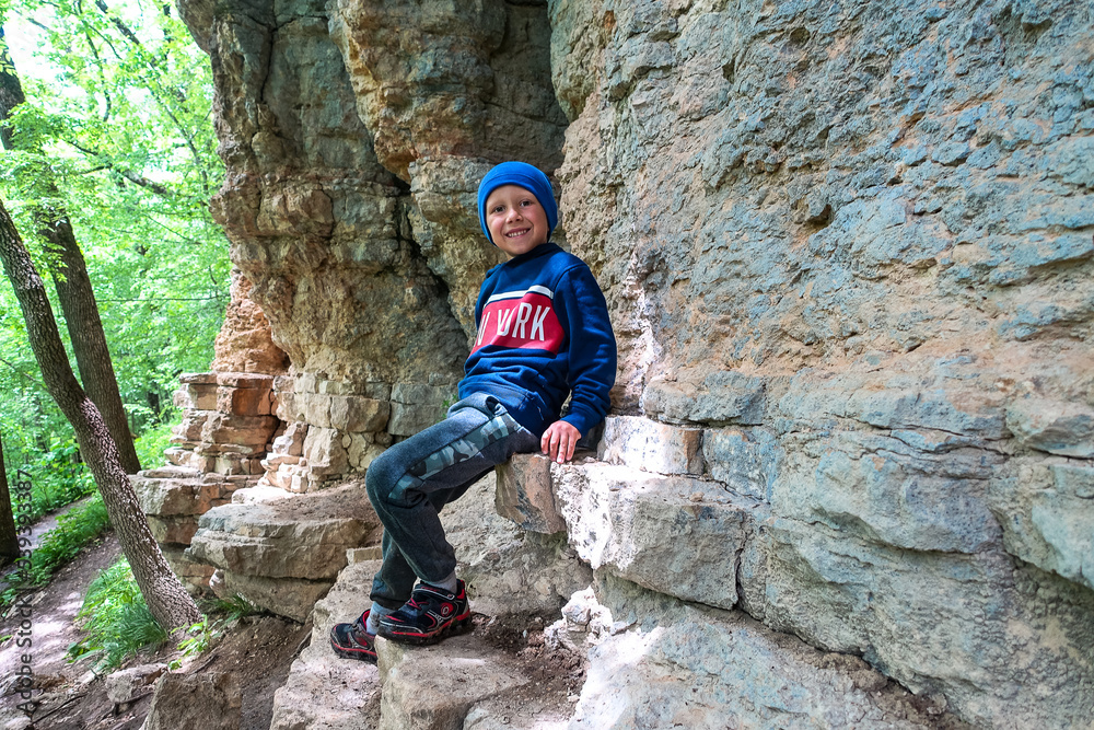 A little boy on the background of rocks in a picturesque forest on the way to the eagle shelf. Mezmai 2021 A little boy on the background of rocks in a picturesque forest on the way to the eagle shelf. Mezmai 2021