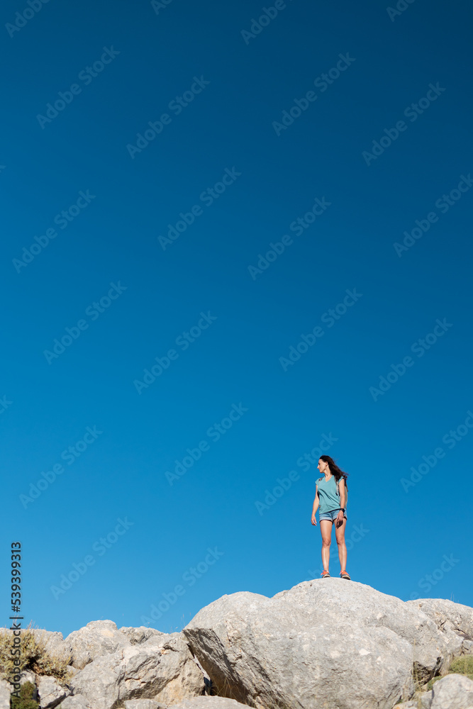 a girl stands on a mountain against a blue sky