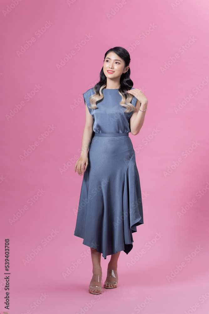 Young smiling woman with trendy dress posing in the studio on pink background. Young smiling woman with trendy dress posing in the studio on pink background.