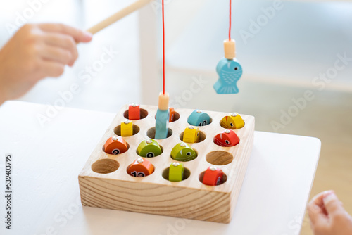 Photography Kids are playing and finding the matched number in the wooden magnetic fishing game, using wooden fishing pole provided with magnets to attach the mouth of the fish and picking it up