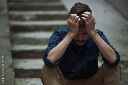 Fotografie Helpless, hurt, depressed young man feeling completely crushed, sitting outside