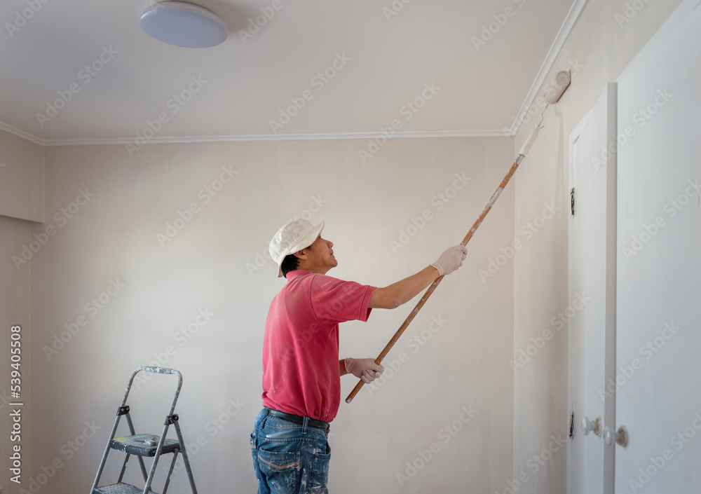 Man painting wall with a roller in home renovation project