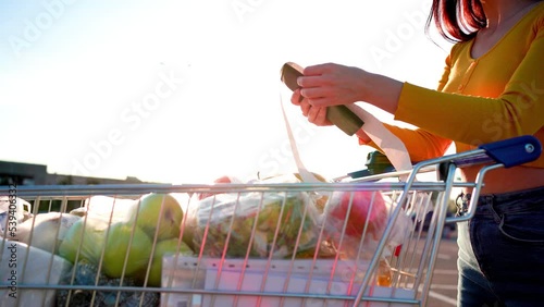 Worried woman checks a paper receipt after grocery shopping at a supermarket. Covid-19 global economy financial crisis concept, money saving. Food and grocery shopping
