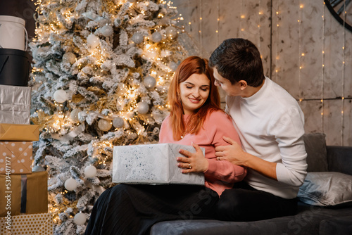 a man and woman are hugging near a christmas tree.