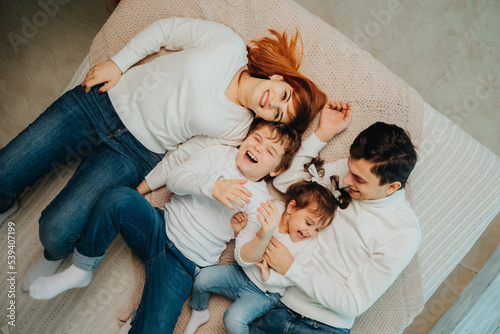 happy laughing family with children in the same white sweaters a laying on the bad and having fun..