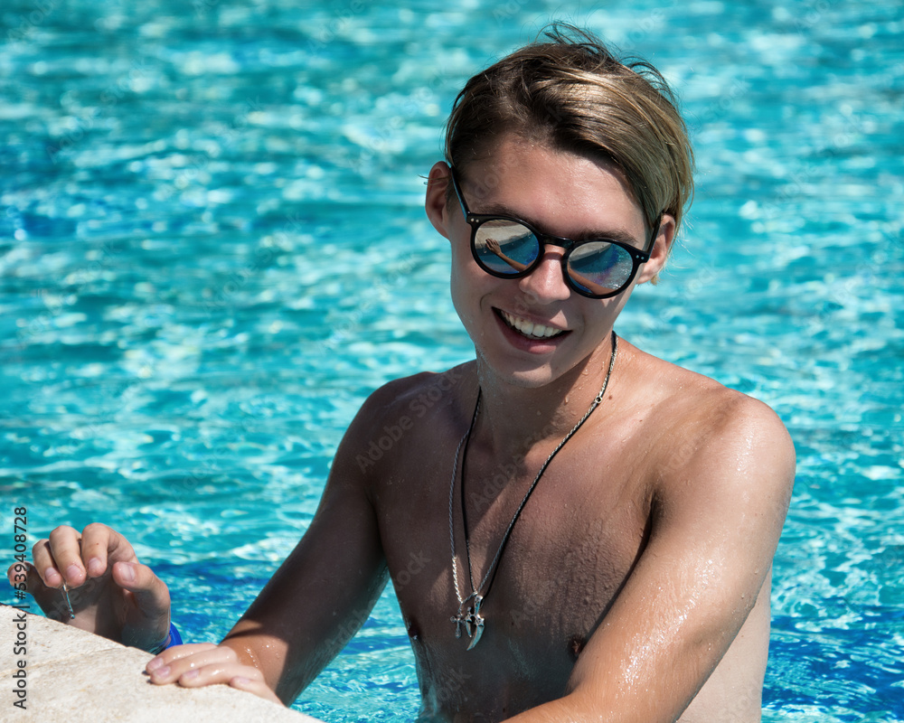Early morning. Vacation and holidays. A young attractive guy is relaxing in the pool.