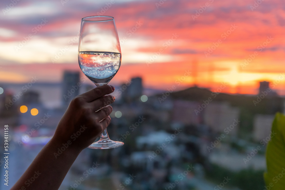A glass of wine in hand, a beautiful sunset outside the window