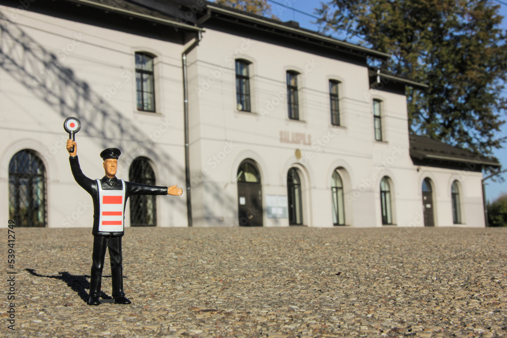 A toy railroad worker in front of railroad station A toy railroad worker in front of railroad station