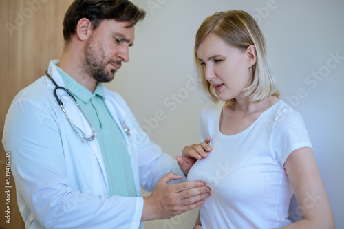 Doctor palpating the painful mammary gland of a woman photo