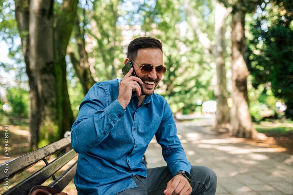 Joyful young adult man, calling his friend, to meet up in the park. Joyful young adult man, calling his friend, to meet up in the park.