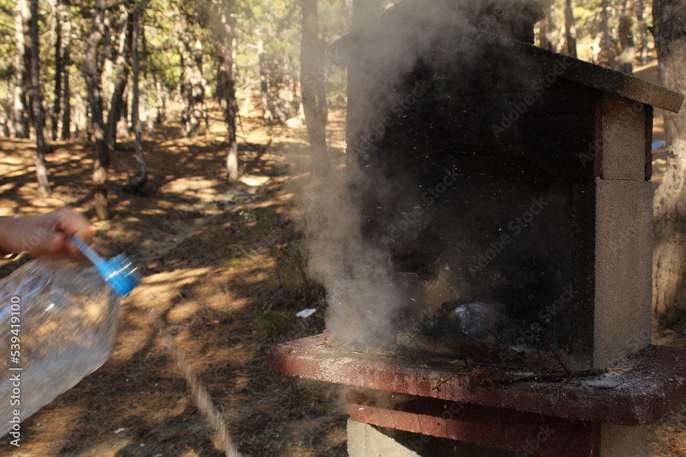 A man hand extinguished the fire in a grill with a bottle of water. Long exposure A man hand extinguished the fire in a grill with a bottle of water. Long exposure