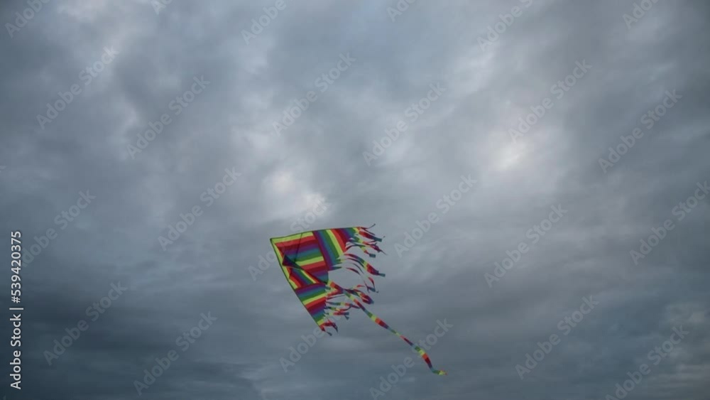 Colorful kite struggling against strong,  stormy wind. Cloudy sky in the background. Darlowko, Poland.
