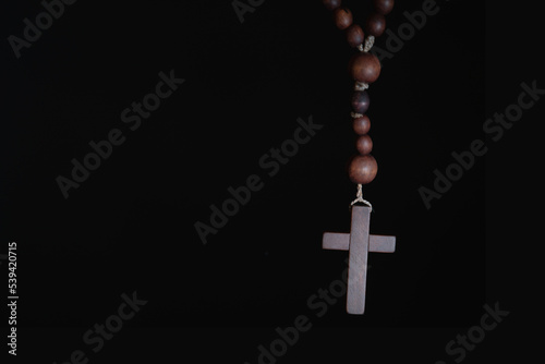 Rosary on black background as a symbol of salvation and eternal life. Copy space.